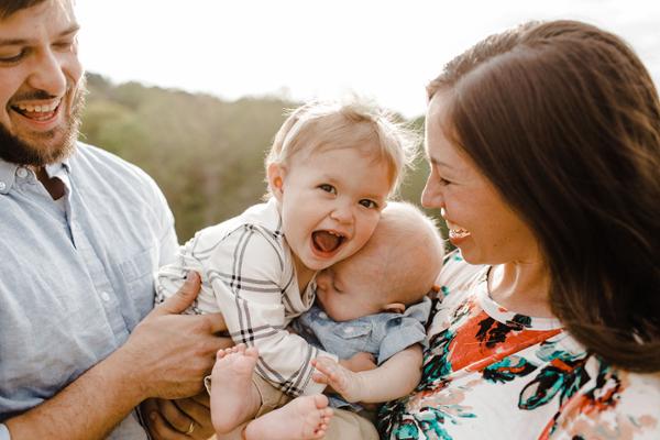 Eine Frau und ein Mann halten zwei Kleinkinder im Arm und lachen.